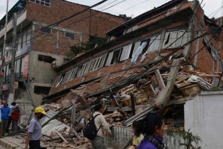 Warga berada dekat bangunan yang ambruk diamuk gempa berkekuatan 7.9 SR di Kathmandu, 25 April 2015.