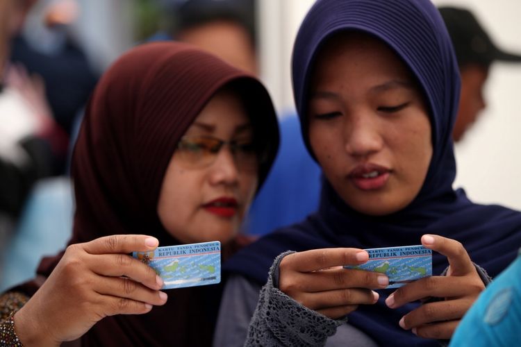 Warga mendapatkan e-KTP yang baru dicetak di stan pelayanan dan pencetakan e-KTP di Taman Mini Indonesia Indah (TMII), Jakarta, Jumat (20/10/2017). Kegiatan yang digelar antara Dinas Kependudukan dan Catatan Sipil DKI bekerja sama dengan Direktorat Jenderal Kependudukan dan Catatan Sipil Kementerian Dalam Negeri ramai diserbu warga yang yang belum memiliki e-KTP.