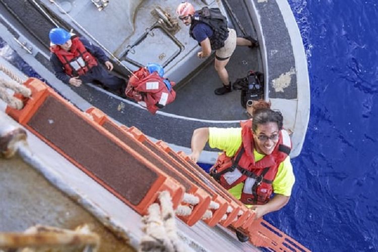 Tasha Fuiaba, perempuan pelayar AS yang telah terkatung-katung di laut selama lima bulan setelah mesin kapal layar mereka rusak, menaiki tangga kapal Angkatan Laut AS, USS Ashland.

