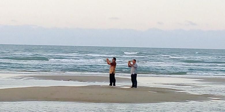 Pengunjung di Pantai Lombang bisa mengabadikan keindahan panorama saat matahari terbenam dari tengah laut ketika air sedang surut. Setiap hari, tidak kurang dari 1.000 pengunjung menikmati pasir yang lembut dan putih untuk melepas lelah sambil merebahkan tubuh di atas pasir. (KOMPAS/AGNES SWETTA PANDIA)