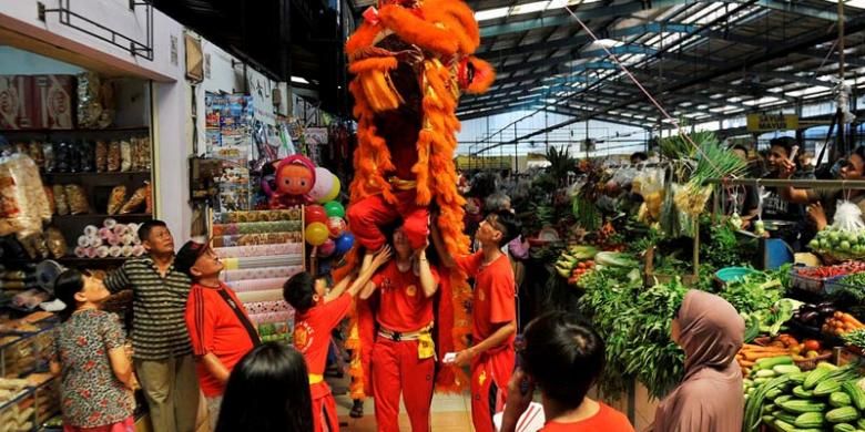 Pemain barongsai mengambil angpau yang disediakan pedagang di depan lapak mereka di Pasar Modern BSD City, Tangerang Selatan, Sabtu (6/2/2016). Barongsai yang berkeliling pasar untuk mengambil angpau tersebut merupakan tradisi menjelang perayaan Imlek.