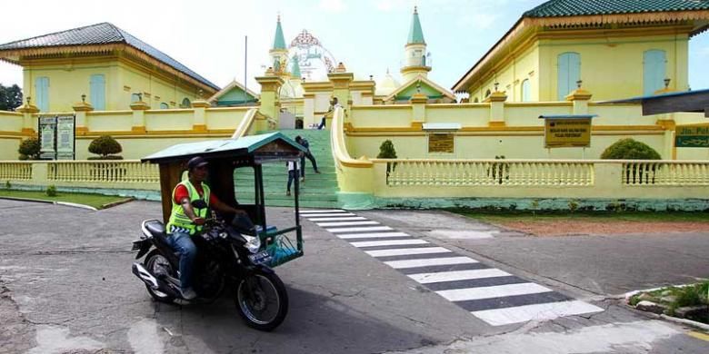 Becak motor melintas di Masjid Raya Sultan Riau atau dikenal sebagai Masjid Penyengat di Tanjung Pinang, Kepulauan Riau. Untuk berkeliling Pulau Penyengat, alternatif transportasi utama adalah becak motor. (KOMPAS/KRIS RAZIANTO MADA)