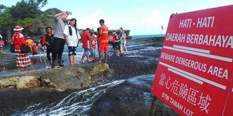 Wisatawan berfoto di area pantai di depan Pura Luhur Tanah Lot, Kabupaten Tabanan, Bali, Minggu (12/6/2016).