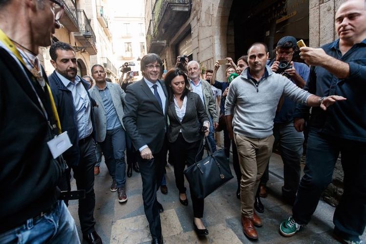 Pemimpin Catalonia Carles Puigdemont (tengah-kiri), yang secara resmi telah dicopot oleh otoritas di Madrid, berjalan didampingi istrinya, Marcela Topor (tengah-kanan) di Girona pada Sabtu (28/10/2017).