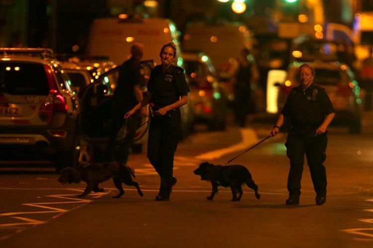 Petugas polisi membawa anjing pelacak di wilayah Finsbury Park, di London utara, setelah sebuah van menabraki sejumlah pejalan kaki pada Senin dinihari (19/6/2017). (AFP/DANIEL LEAL-OLIVAS)