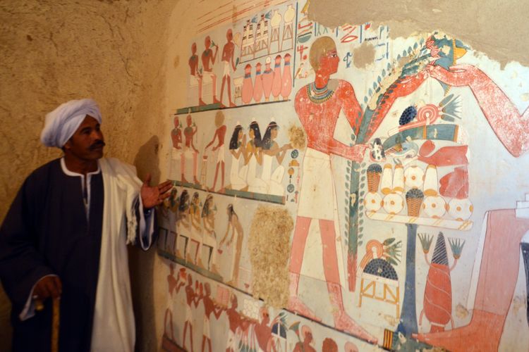 Seorang pekerja Mesir berdiri di samping lukisan yang ditemukan di Kampp 161 pada December 9, 2017. 
