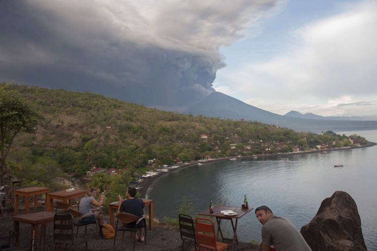 Sejumlah wisatawan menyaksikan letusan Gunung Agung dari Pantai Jemeluk, Karangasem, Bali, Minggu (26/11/2017). Pusat Vulkanologi dan Mitigasi Bencana Geologi menyatakan telah terjadi letusan freatik kedua pada pukul 17.20 Wita yang disusul dengan semburan asap dan abu vulkanis hingga ketinggian 3.000 meter.