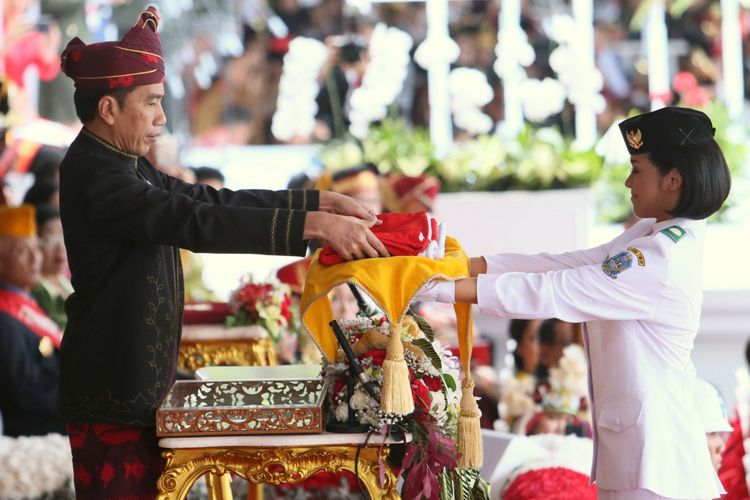 Presiden Joko widodo menyerahkan Bendera Merah Putih kepada Anggota Paskibraka Perwakilan dari Jawa Timur Fariza Putri S untuk dikibarkan dalam Upacara Peringatan Detik-detik Proklamasi Kemerdekaan Republik Indonesia di Halaman depan Istana Merdeka, Jakarta, Kamis (17/8/2017). Kompas/Wisnu Widiantoro (NUT) 17-08-2017