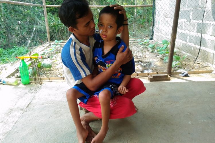 Teuku Muh Guci S Sugiyanto (33) memangku Ananda Yue Riastanto (8) di teras rumahnya di RT 27/14 Pedukuhan Dhisil, Desa Salamrejo, Kecamatan Sentolo, Kabupaten Kulon Progo, Sabtu (9/9/2017).