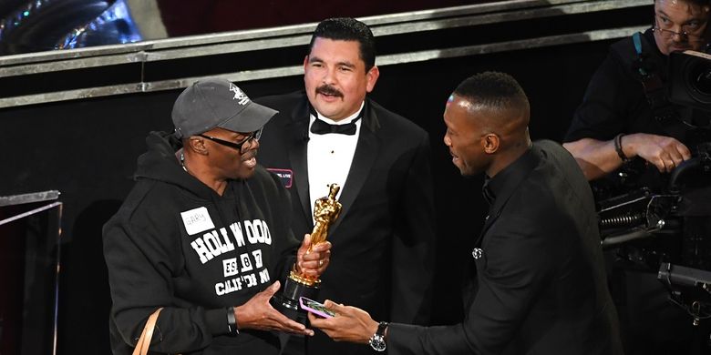 Aktor Mahershala Ali (kanan) mengizinkan seorang turis memegang Piala Oscar-nya pada perhelatan Academy Awards di Dolby Theater, Hollywood, California, Minggu (26/2/2017).