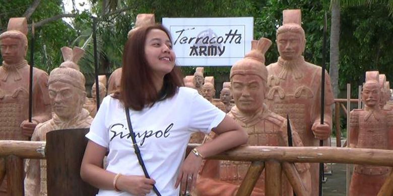     Pengunjung, Vivi, saat berfoto dengan latar Patung Terakota di Pantai Tongaci Sungailiat, Bangka, Kepulauan Bangka Belitung. 