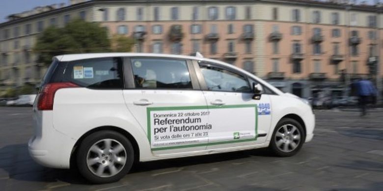 Sebuah taksi meluncur di jalanan kota Milan, Italia dengan ajakan menggelar referendum ditempelkan di badan mobil itu.(MIGUEL MEDINA/AFP )