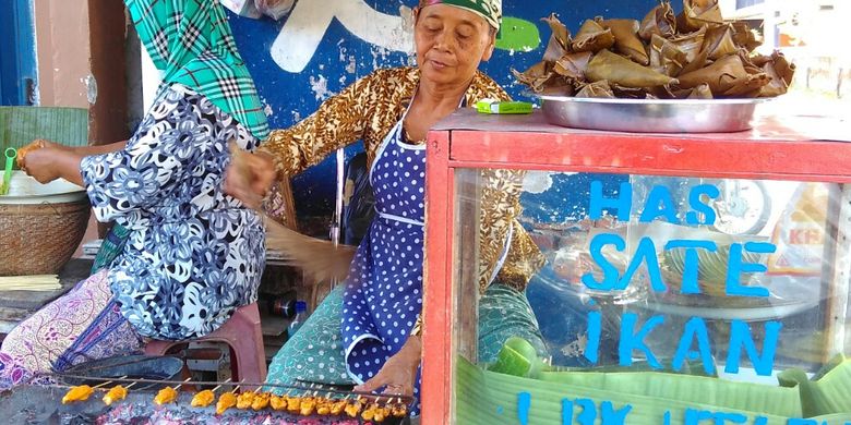 Salah satu pedagang sate ikan Tanjung tengah membakar sate.