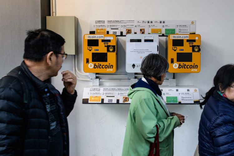 Sejumlah orang melintasi mesin ATM bitcoin di Hongkong. Gambar diambil pada 18 Desember 2017.