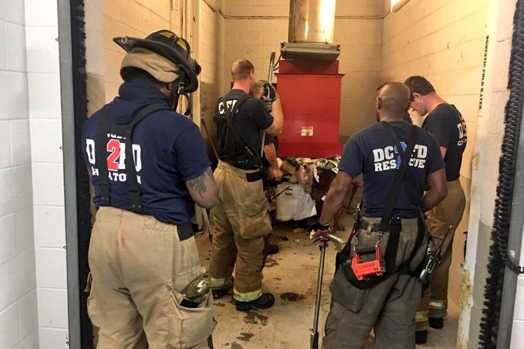 Para petugas dinas pemadam kebakaran Washington DC berupaya menyelamatkan seorang pria yang terjatuh dan terjebak di sistem pembuangan sampah di sebuah apartemen.