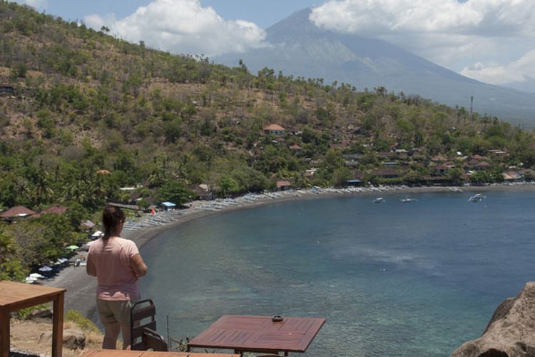 Seorang wisatawan menikmati pemandangan di Pantai Desa Amed, Karangasem, Bali, Jumat (29/9/2017). Kementerian Pariwisata menyatakan, secara umum pariwisata Bali masih normal meskipun terjadi peningkatan aktivitas Gunung Agung yang saat ini pada level awas.
