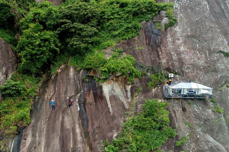 Reporter Kompas.com dibantu pemandu menyeberangi tyrolean untuk mencapai hotel gantung Padjajaran Anyar yang terletak di tebing Gunung Parang, Purwakarta, Jawa Barat setinggi 500 meter difoto menggunakan drone, Minggu (19/11/2017). Hotel gantung ini diklaim sebagai hotel gantung tertinggi di dunia mengalahkan ketinggian hotel gantung di Peru.