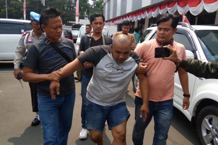 Baihazi Sakom alias Boy (34), pemerkosa terhadap seorang perempuan di Depok pada pekan lalu, tampak berjalan dengan kaki pincang saat dibawa ke Mapolresta Depok pada Rabu (30/8/2017). Boy disebut sempat berupaya kabur saat disergap polisi di tempat persembunyiannya di Cilebut, Kabupaten Bogor pada Rabu dinihari. Polisi akhirnya melepaskan tembakan yang mengenai kaki kiri Boy. (Kompas.com/Alsadad Rudi)