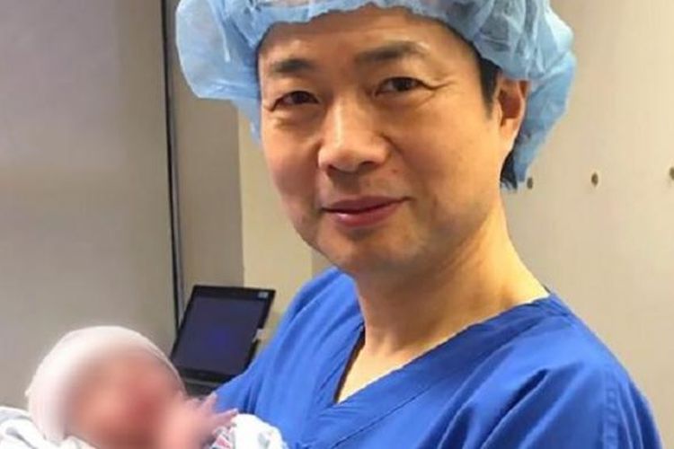 John Zhang menggendong bayi dari tiga orang tua kandung hasil langkah kontroversial yang ditempuhnya. 