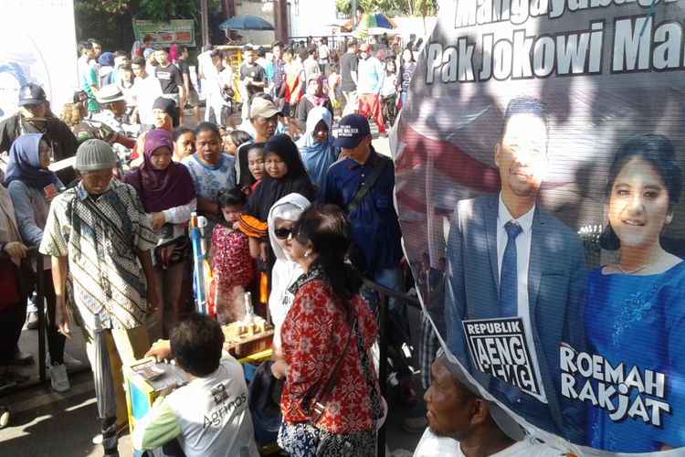 Pengunjung mengantre mendapatkan kue Putu Bambu dalam acara syukuran pernikahan putri Presiden Jokowi di car free day (CFD) Jl Slamet Riyadi Solo, Minggu (5/11/2017).(Kompas.com/Labib Zamani)