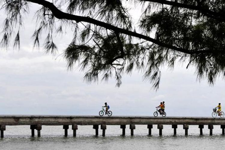 Pengunjung bersepeda menyusuri Jembatan Cinta di Pulau Tidung, Sabtu (14/3/2015). Keindahan pantai di Pulau Tidung, Kepulauan Seribu, menjadi salah satu daya tarik wisatawan untuk berkunjung ke pulau ini.