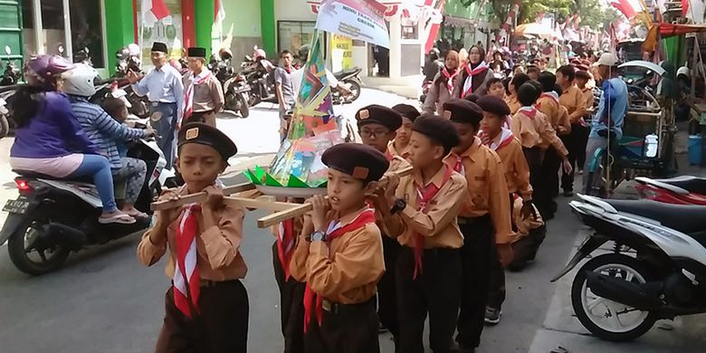 


Tumpeng buku berukuran kecil saat diarak siswa MINU Trate Putra Gresik di sekitar sekolah, Senin (14/8/2017).(KOMPAS.com / Hamzah)