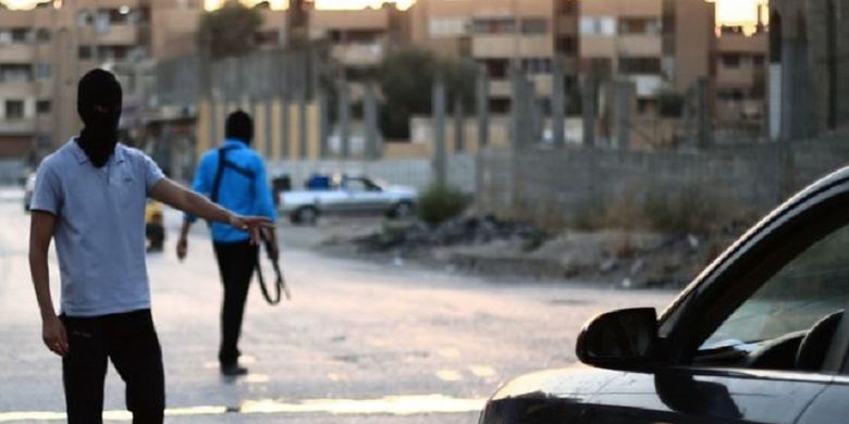 Dua orang anggota polisi ISIS menghentikan kendaraan di salah satu titik kota Raqqa, Suriah utara.