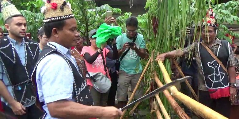 Kepala Dinas Pariwisata Lamandau, Frans Evendi, memotong kayu rintangan dalam upacara Garung Pantan, upacara penyambutan tamu dalam adat Dayak, di Desa Lopus, Kabupaten Lamandau, Kalimantan Tengah, Jumat (30/11/2017). 