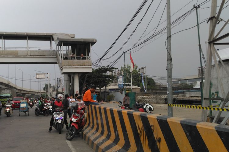 Pengendara motor berhenti di pinggir jalan untuk melihat aksi nekat Agustinus di SUTET daerah Tanjung Priuk, Jakarta Utara, Selasa (15/8/2017).