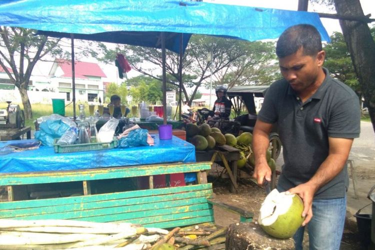 


Pedagang mengupas kelapa muda di Jalan Lingkar Stadion Tunas Bangsa, Kota Lhokseumawe, Aceh, Minggu (7/1/2018).(KOMPAS.com/MASRIADI)