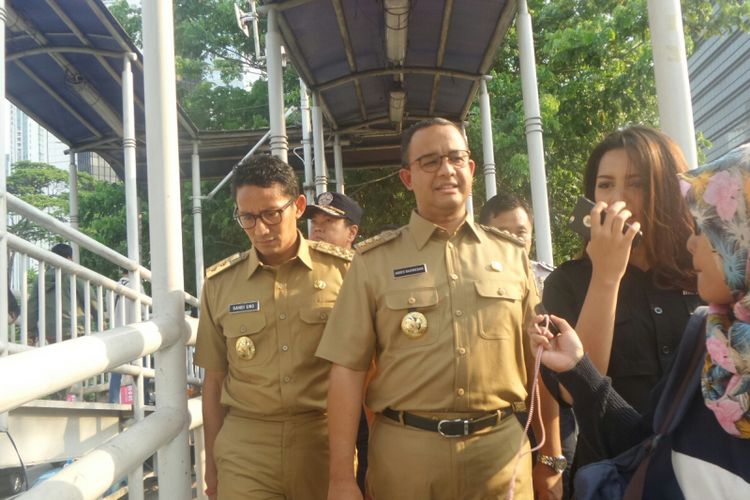 Gubernur DKI Jakarta Anies Baswedan dan Wakil Gubernur Sandiaga Uno di Halte Dukuh Atas saat akan menaiki bus transjakarta, Selasa (17/10/2017). 