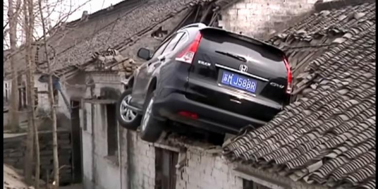 Honda CR-V yang tersangkut di atap rumah di China.